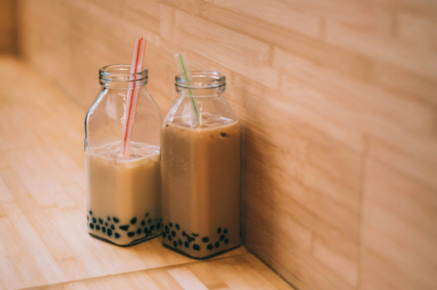 Two glasses of boba milk tea with visible tapioca pearls.